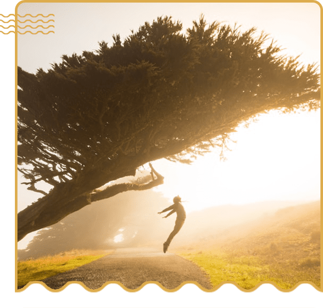 A person jumping in the air next to a tree.