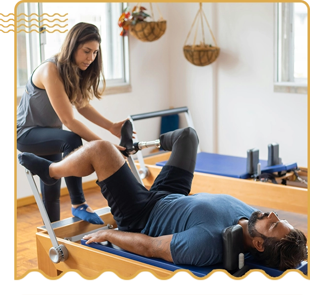 A woman helping a man on a pilates machine.