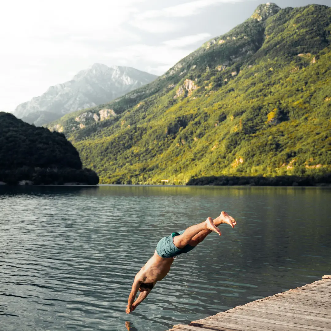 A man jumping into the water from a dock.